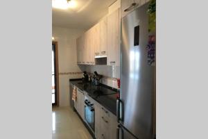 una cocina con nevera de acero inoxidable y armarios de madera en Villa Matilde Modern 2 Bedroom Apartment Close to Beach, en San Luis de Sabinillas