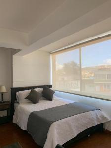 a bedroom with a large bed with a large window at Hotel Santa Elena Norte in Tunja