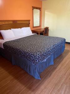 a large bed in a hotel room with a desk at Lariat Motel in Moriarty