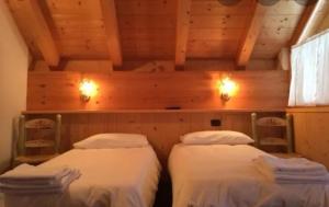 two twin beds in a room with wooden ceilings at Locanda Rondolost in Cencenighe