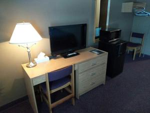 a desk in a hotel room with a television and a lamp at Shoal Lake Motor Inn in Shoal Lake