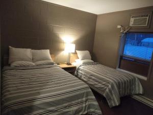 a hotel room with two beds and a lamp at Shoal Lake Motor Inn in Shoal Lake