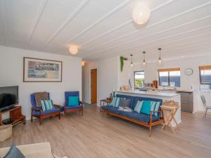 a living room with a couch and chairs and a kitchen at Shore Beats Work - Whangamata Holiday Home in Whangamata