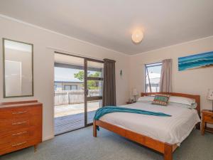 a bedroom with a bed and a large window at Shore Beats Work - Whangamata Holiday Home in Whangamata