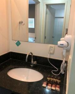 uma casa de banho com lavatório, secador de cabelo e espelho em Flat inteiro - Aldeia das águas em Barra do Piraí