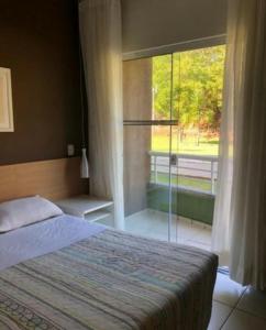 um quarto com uma cama e uma grande janela em Flat inteiro - Aldeia das águas em Barra do Piraí
