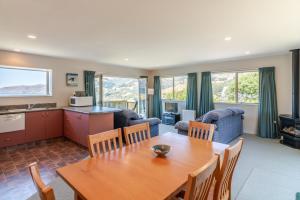 a living room with a wooden table and a kitchen at Seaview Outlook - Wainui Holiday Home in Wainui