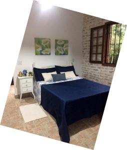 a bedroom with a bed with a blue comforter at Ville France - Chalé Côte d'Azur a 5 min do Centro in Camanducaia