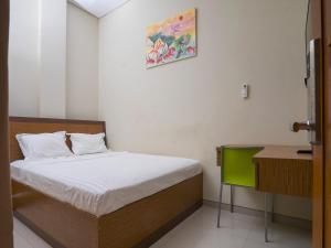 Un dormitorio con una cama y un escritorio y un cuadro. en Pondok Indah Guest House by ecommerceloka, en Samarinda