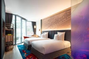 a hotel room with two beds and a large window at Hotel Indigo Phuket Patong, an IHG Hotel in Patong Beach