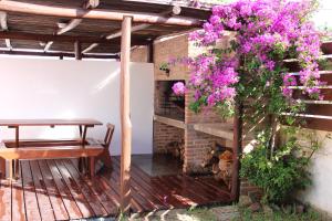 a patio with a table and purple flowers at Koe Porá in Punta Del Diablo
