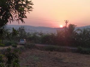 un coche conduciendo por una carretera al atardecer en Jiten Homestay, en Anjuna