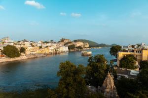 a view of a river with buildings and a city at Hanuman Ghat Boutique Stays by Cafe Helsinki in Udaipur +28 photos
