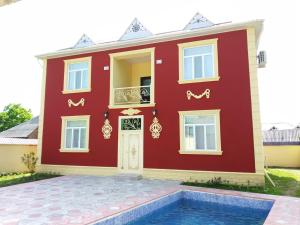 a red house with a pool in front of it at Villa SUPER in Gabala