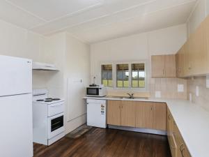 a kitchen with white appliances and wooden cabinets at Reflections Yamba Lighthouse Cottages in Yamba