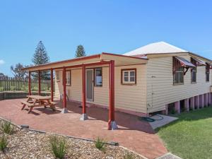 a small house with a picnic table and a bench at Reflections Yamba Lighthouse Cottages in Yamba