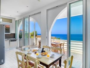 Villa Anemos by Estia في كالاثاس: غرفة طعام مع طاولة وإطلالة على المحيط