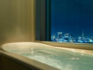 a bath tub sitting in front of a window at Mitsui Garden Hotel Ginza Premier in Tokyo