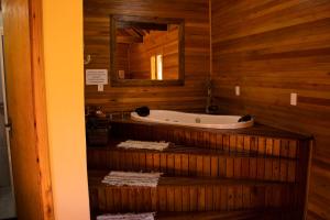 a bathroom with a tub on a wooden wall at Pousada Cascata Véu de Noiva in Urubici