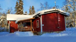 a red cabin with snow on the roof in the snow at Holiday Home Ivalo in Ivalo