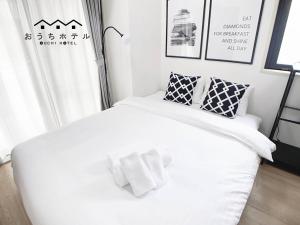 a white bed with two pillows on top of it at OUCHI HOTEL Takaramachi in Hiroshima