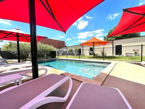 a pool with umbrellas and chairs and a swimming pool at Adelphi Apartments 1 or 1A in Echuca