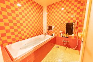 a bathroom with a large tub and orange tiles at Nagasaki Chapel Coconuts Hotel ＆Resort in Isahaya