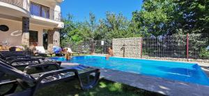 een zwembad met stoelen en mensen in een tuin bij Calea Poienii Penthouse in Braşov