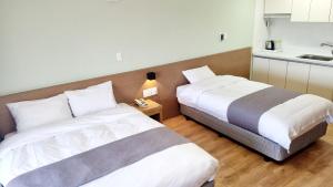 dos camas sentadas una al lado de la otra en una habitación en Hi Jeju Hotel, en Jeju