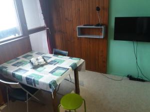 Cette chambre dispose d'une télévision et d'une table avec des chaises. dans l'établissement studio aux pieds des pistes, à Besse-et-Saint-Anastaise