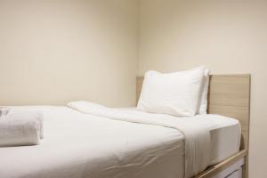 Best Location 2BR Tamansari La Grande Apartment By Travelio في باندونغ: غرفة نوم بها سرير مع ملاءات ووسائد بيضاء +14 صورة