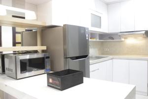 Best Location 2BR Tamansari La Grande Apartment By Travelio في باندونغ: مطبخ مع دواليب بيضاء وميكرويف