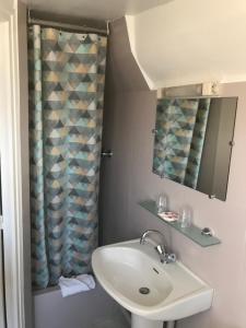 łazienka z umywalką i zasłoną prysznicową w obiekcie Hôtel L'Estran w mieście Trouville-sur-Mer