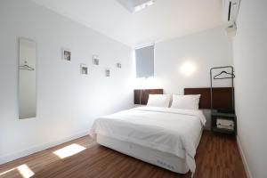 a white bedroom with a large bed with white sheets at Ekonomy Haeundae Hostel in Busan
