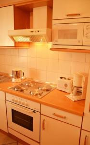 a kitchen with a stove and a microwave at Landhaus Braband Ferienhaus - Rugenbargsweg 23 in Cuxhaven