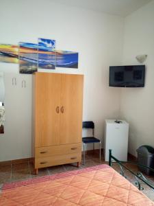 1 dormitorio con armario de madera y TV en la pared en B&B Express, en Leverano