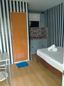 Habitación pequeña con cama y puerta de color naranja en DJCI Apartelle Small Rooms, en Cabanatúan