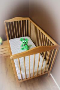 a crib with a green teddy bear sitting in it at Gîte De La Souris Verte in Molamboz