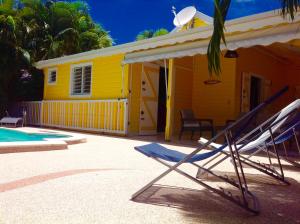 a yellow house with two lounge chairs in front of it at La Villa Madinina in Les Trois-Îlets