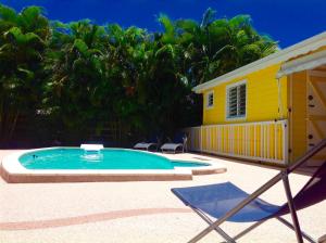 レ・トロワ・イレにあるLa Villa Madininaの黄色い家の前のスイミングプール