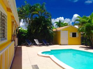 レ・トロワ・イレにあるLa Villa Madininaの黄色い家の前のスイミングプール