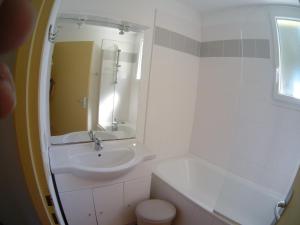 een witte badkamer met een wastafel en een spiegel bij La Pointe du Soleil in Le Verdon-sur-Mer