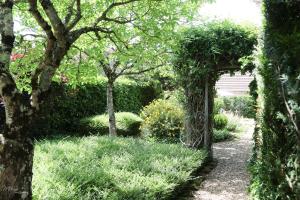 an archway in a garden with bushes and trees at Gîte De La Souris Verte in Molamboz