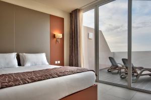 a bedroom with a bed and a balcony with chairs at Mayflower Hotel Malta in St. Paul's Bay +58 photos