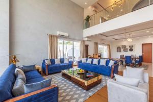 a large living room with blue couches and a table at StayVista's White Pebbles - A Villa with Theater Room & Swimming Pool in Lonavala +51 photos