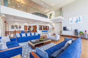 a large living room with blue couches at StayVista's White Pebbles - A Villa with Theater Room & Swimming Pool in Lonavala