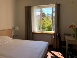 1 dormitorio con cama blanca y ventana en Hotel Neufeld en Zúrich