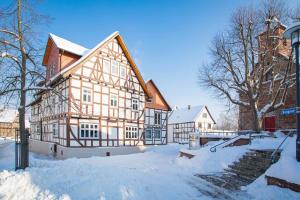 a large wooden building with snow on the ground at Hotel-Pension Eschwege in Eschwege