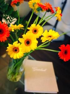蘇黎世的住宿－諾伊菲爾德酒店，花瓶,花瓶上满是黄红花,花瓶旁边放着一张卡片