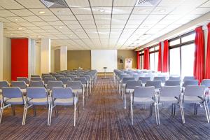 a room with rows of chairs and red curtains at Mercure Saint-Lary in Saint-Lary-Soulan
